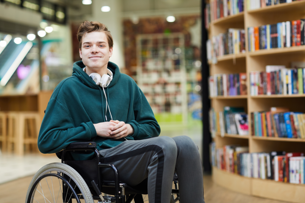 Young man sitting in a wheelchair in a library