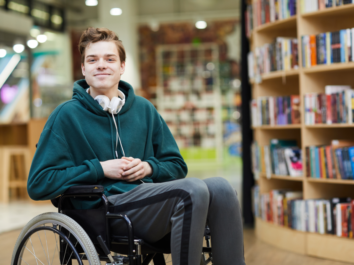 Image of young person sitting in a wheelchair in a library