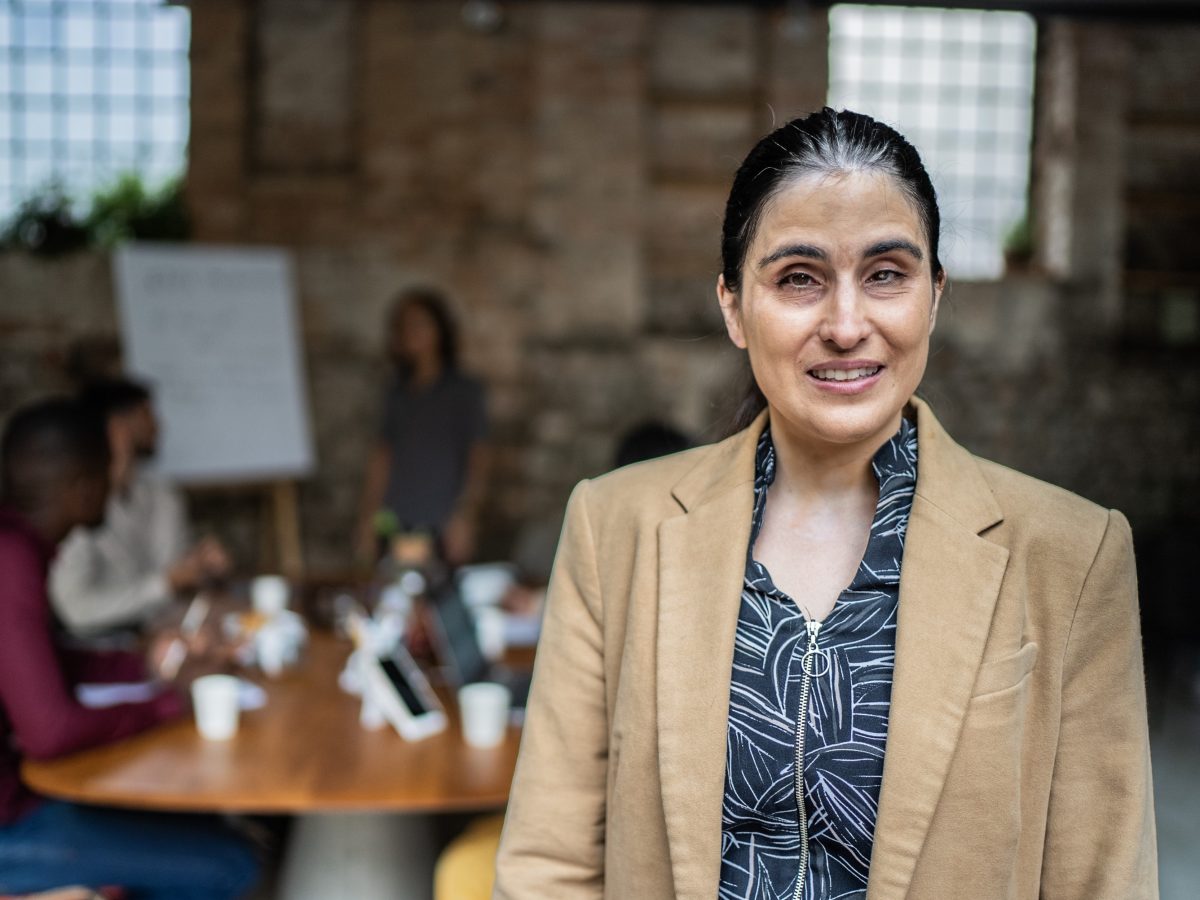 Woman facing camera meeting in background