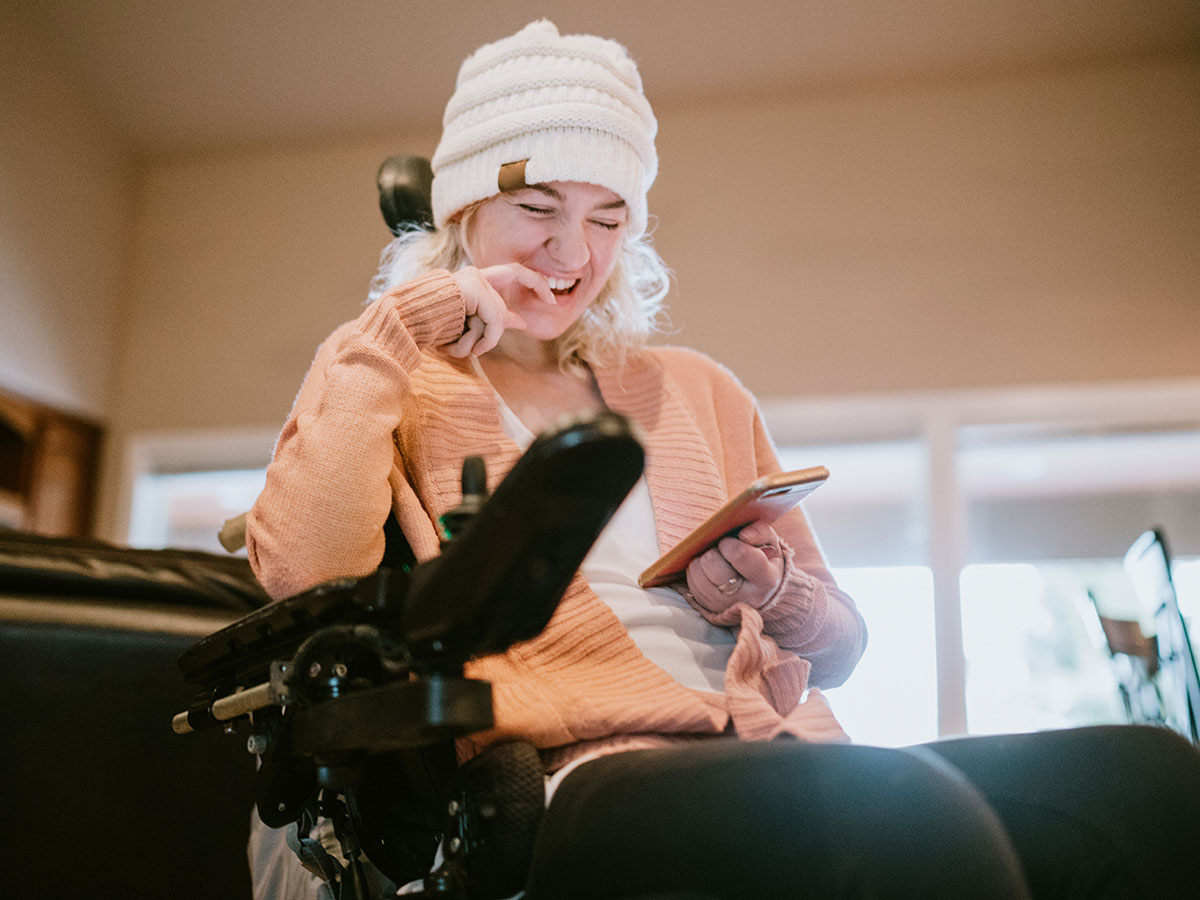 Woman laughing in wheelchair looking at phone